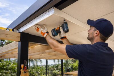 Builder installing insulated roofing panels for a modern patio structure.