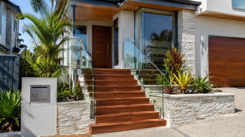 Custom hardwood front staircase at a modern Southport home with glass balustrades.