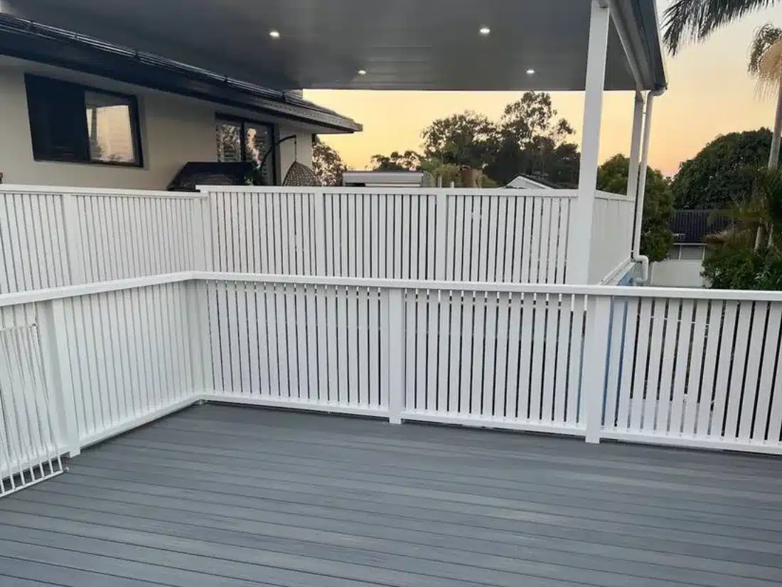 Grey composite deck with white slat balustrade joined to an insulated patio roof