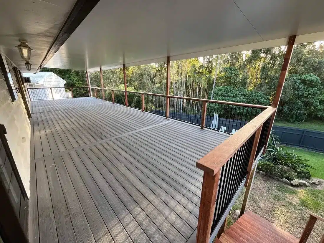 Elevated composite deck with hardwood handrails, black balustrade and a full-length insulated patio roof
