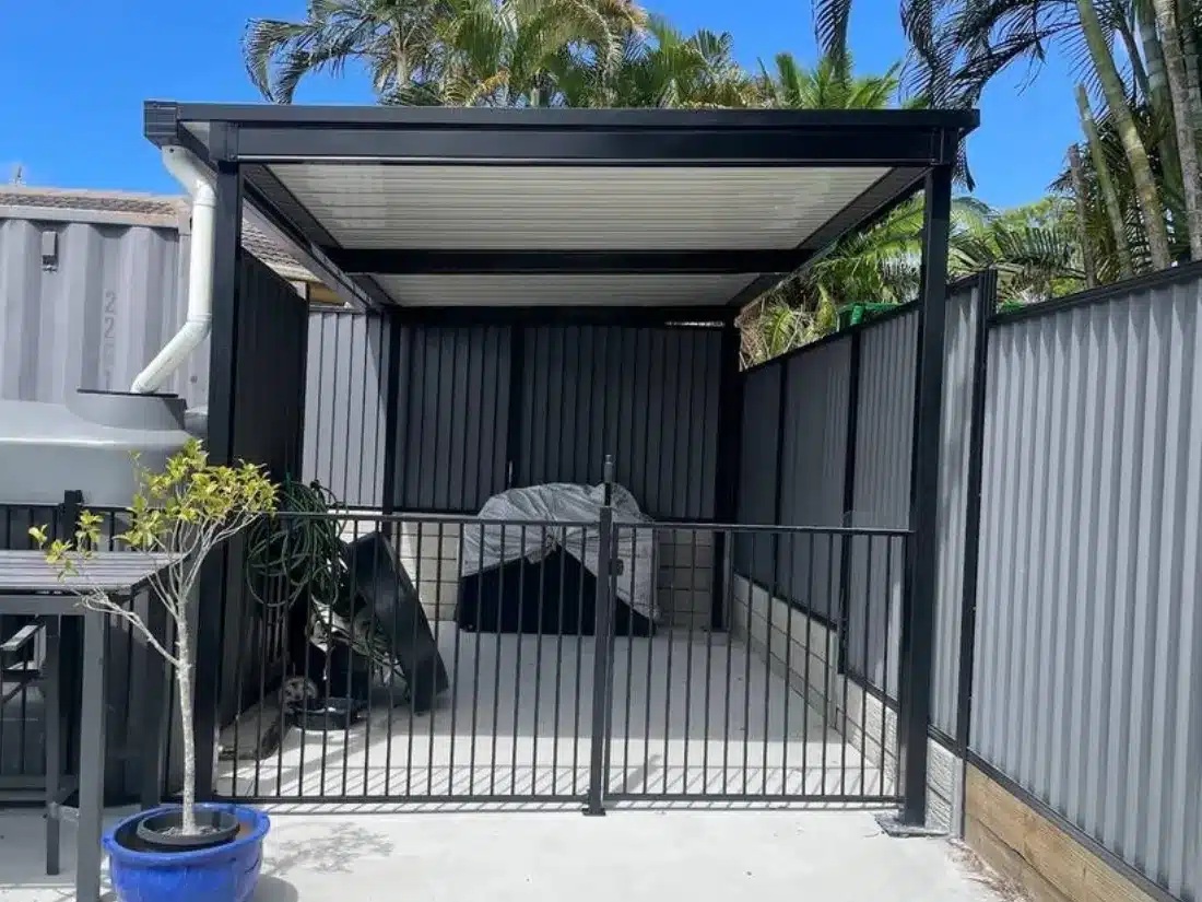 Freestanding flat roof patio with black posts and beams over a concrete pad