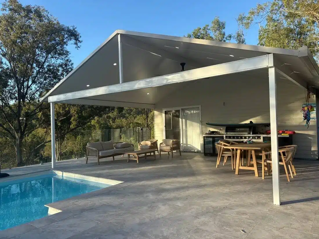 White gable insulated patio over a tiled pool terrace with outdoor kitchen and dining area